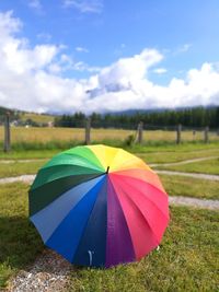 Multi colored umbrella on field against sky