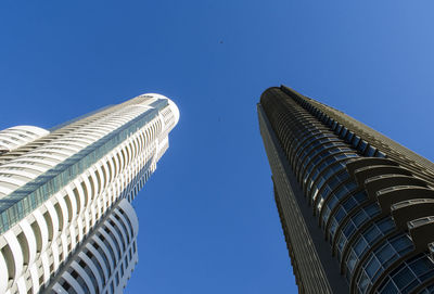 Low angle view of modern buildings against clear blue sky