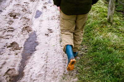 Low section of man walking on dirt road