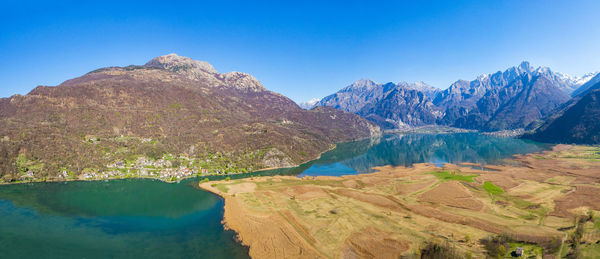 Scenic view of lake and mountains against clear blue sky