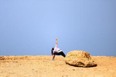 Full length of woman on rocks against clear sky