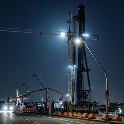 Illuminated street lights against sky at night