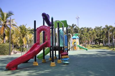 Playground in park against clear blue sky