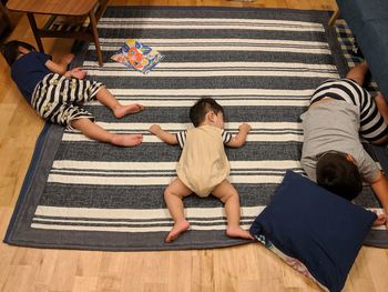 High angle view of siblings lying on floor at home