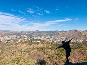 Rear view of man standing on mountain against sky