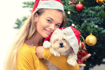 Portrait of woman with dog on christmas tree