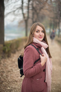 Portrait of smiling woman standing against tree