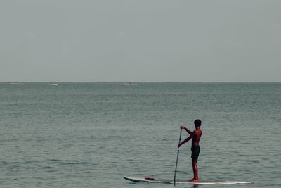 Man standing in sea against sky