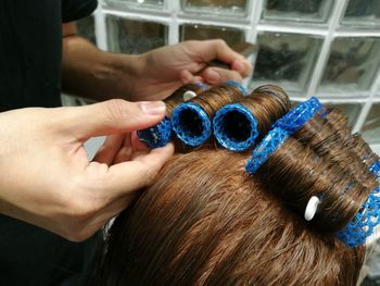 Cropped hands of hairdresser applying hair curlers on woman