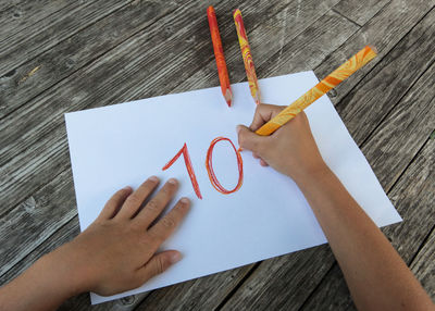 Directly above shot of woman hand holding paper on table