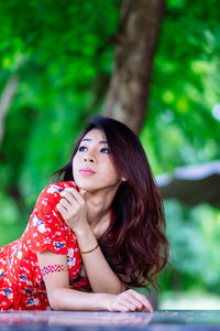 Young woman looking away while standing outdoors