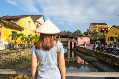 Woman standing by houses against sky