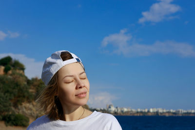 Portrait of young woman against sky