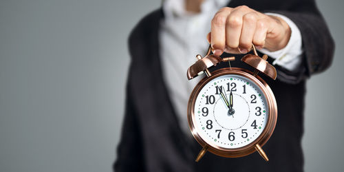 Close-up of human hand holding clock