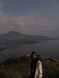 Portrait of smiling man standing on mountain against sky