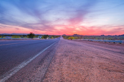 Empty road against sky during sunset