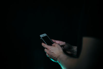 Midsection of man using mobile phone against black background