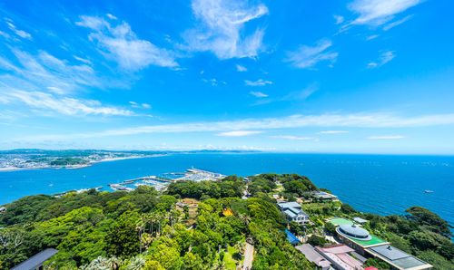 High angle view of townscape by sea against blue sky