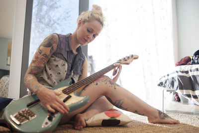 Woman playing guitar at home