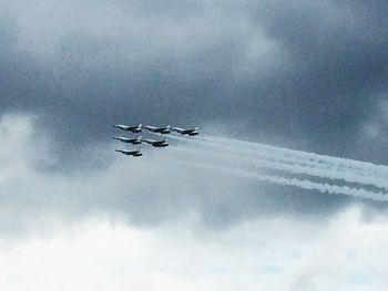 Low angle view of airplane flying in cloudy sky