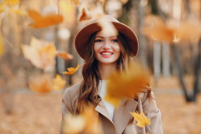 Portrait of young woman standing against trees