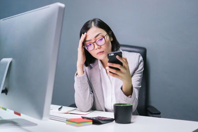 Woman using mobile phone while sitting on table