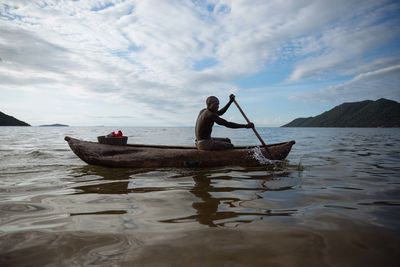 Man fishing in sea against sky