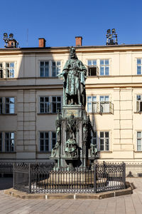Statue against building in city against clear sky