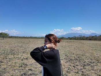 Side view of woman standing on land against sky