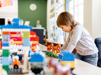 Toddler plays with toy blocks. little boy with toy constructor. interior of kindergarten or nursery.