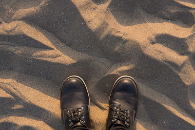 Low section of man standing at sandy beach