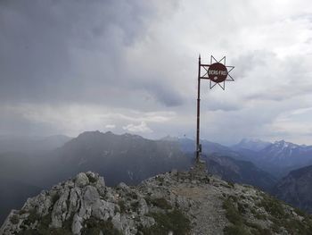 Cross on rock against sky