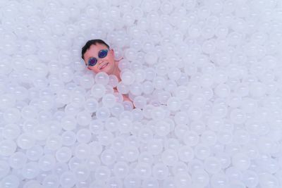 High angle view of boy lying with white balls