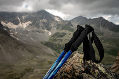 Trekking poles close-up, lie on a stone overgrown with grass, in summer, against the backdrop of