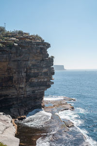 Rock formation on sea against clear sky