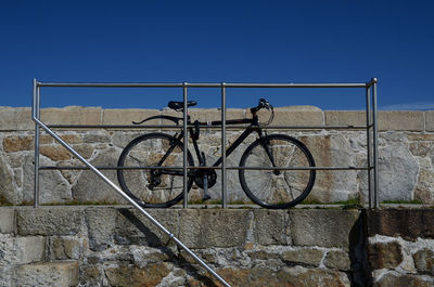 Low angle view of bicycle parked by railing on footpath