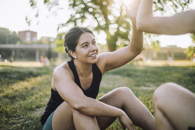 Exhausted woman giving high-five to friend while sitting at park