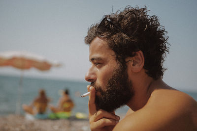 Close-up of shirtless man smoking cigarette at beach