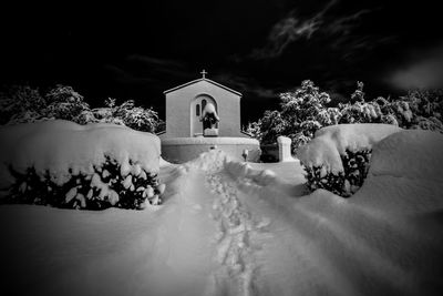 Church by building against sky during winter