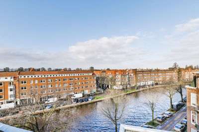 Buildings by canal against sky in city