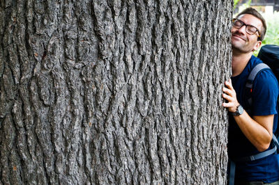 Man standing by tree trunk