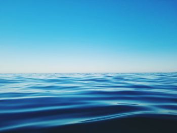 Surface level of sea against clear blue sky