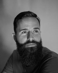 Man with long beard looking away against gray background