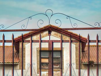 Low angle view of closed gate of building against sky