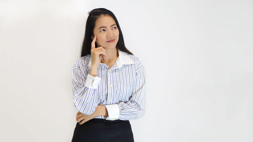 Businesswoman contemplating while standing against white background