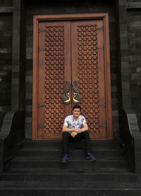 Full length portrait of man sitting on staircase of building