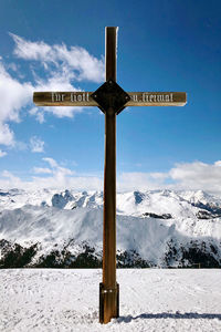 Information sign on snowcapped mountain against sky