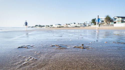 People on beach against clear sky