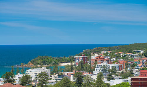 Aerial view of townscape by sea against sky