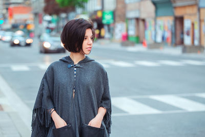 Young woman standing on road in city